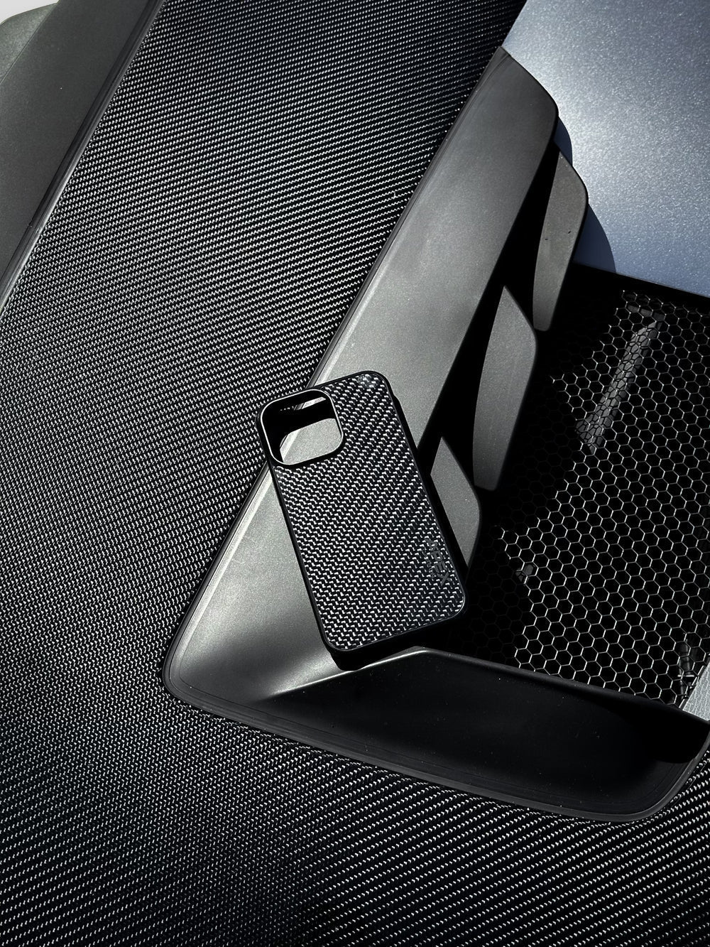 CARBON FIBER PHONE CASE from the "carbon" collection of Icon Cases on the hood of a sports car